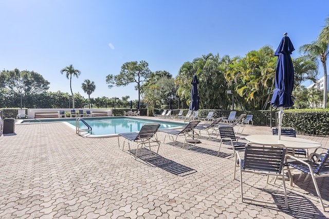 community pool with a patio area and fence
