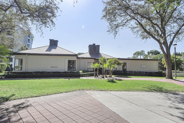 rear view of property with a yard, stucco siding, and a chimney