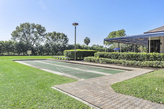 view of property's community featuring a yard and shuffleboard