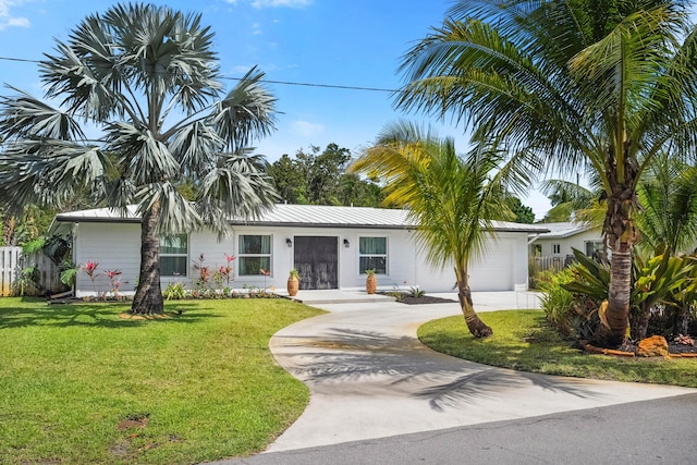 view of front facade featuring fence, an attached garage, a front yard, concrete driveway, and metal roof