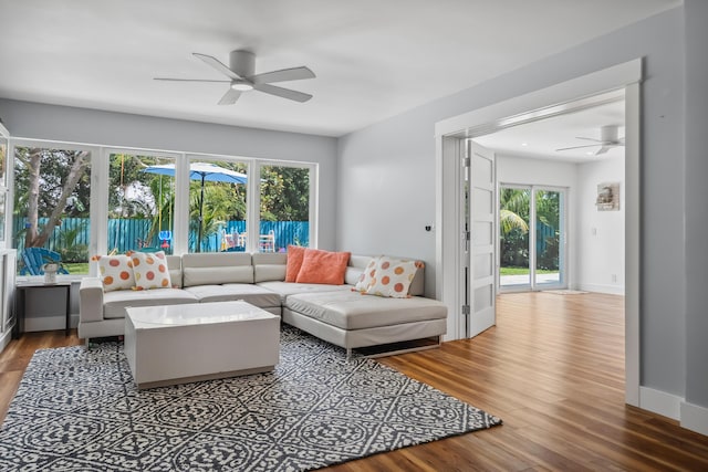 living area with baseboards, a ceiling fan, and wood finished floors