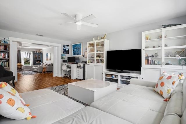 living area with a ceiling fan, visible vents, and wood finished floors