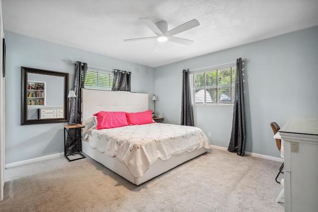 carpeted bedroom featuring baseboards, multiple windows, and a ceiling fan