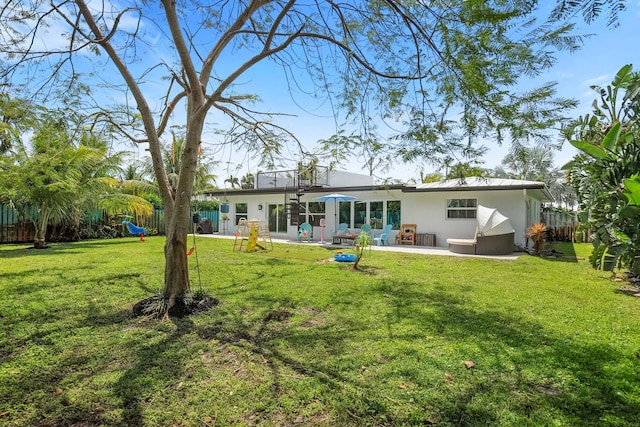 rear view of house featuring a patio, stucco siding, fence, and a yard