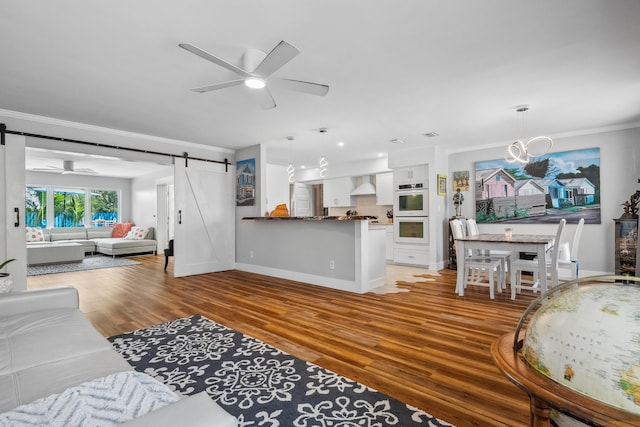 living area featuring ornamental molding, a ceiling fan, light wood finished floors, and a barn door
