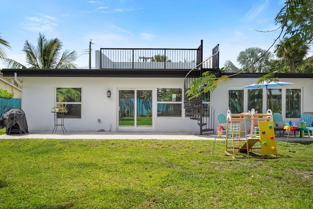 rear view of property with a patio, a balcony, stucco siding, and a yard