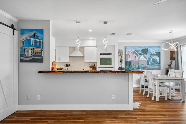 kitchen with backsplash, ornamental molding, custom range hood, white cabinetry, and oven