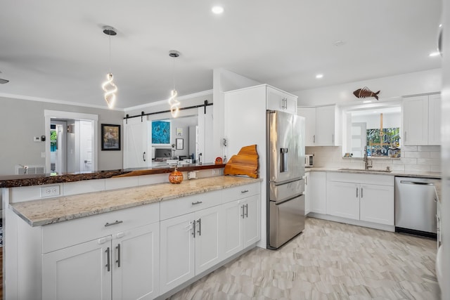 kitchen featuring decorative backsplash, appliances with stainless steel finishes, a sink, a peninsula, and white cabinetry