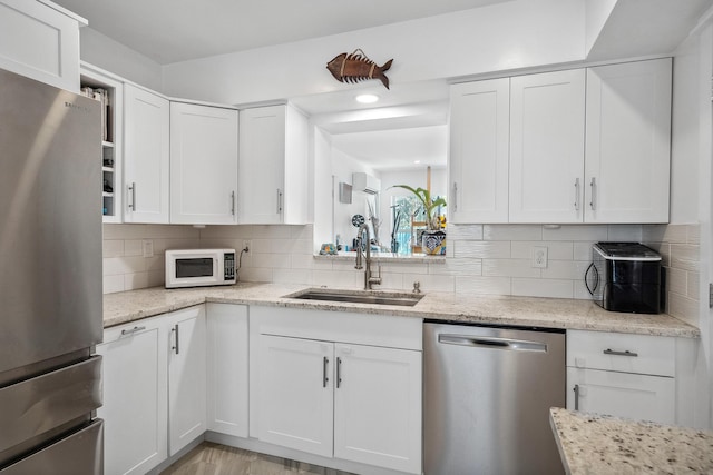 kitchen featuring a sink, backsplash, white cabinets, and stainless steel appliances