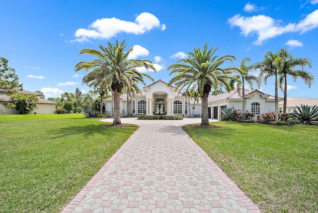 mediterranean / spanish home featuring curved driveway, a front yard, and stucco siding