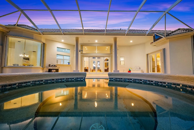 pool at dusk with an outdoor pool, french doors, and glass enclosure