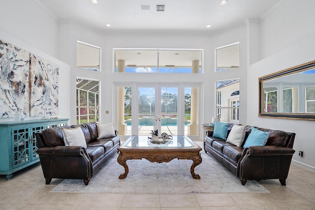 living room featuring tile patterned floors, a high ceiling, ornamental molding, and visible vents