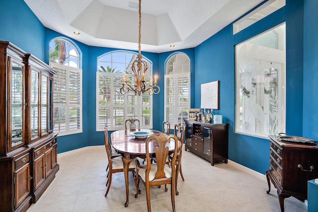 dining space with an inviting chandelier, light tile patterned floors, a tray ceiling, a textured ceiling, and baseboards