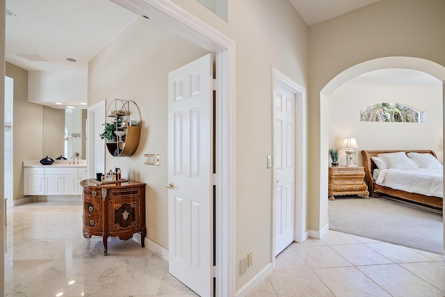 hall with a sink, visible vents, baseboards, and arched walkways