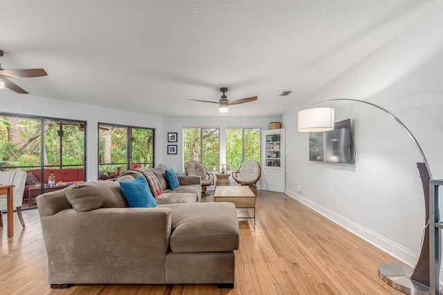 living area featuring baseboards, visible vents, a ceiling fan, and light wood-style flooring