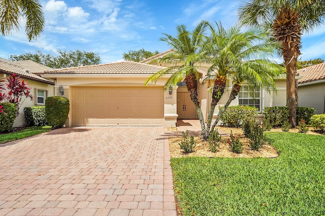 6298 Via Primo St, Lake Worth, FL 33467 - mediterranean / spanish home featuring decorative driveway, stucco siding, a tile roof, a garage, and a front lawn