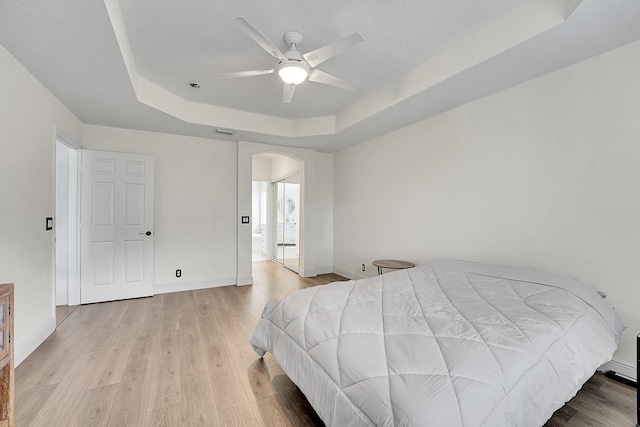 6298 Via Primo St, Lake Worth, FL 33467 - bedroom with a tray ceiling, arched walkways, light wood-type flooring, and baseboards