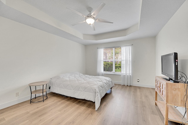 6298 Via Primo St, Lake Worth, FL 33467 - bedroom with light wood finished floors, a raised ceiling, baseboards, a ceiling fan, and a textured ceiling
