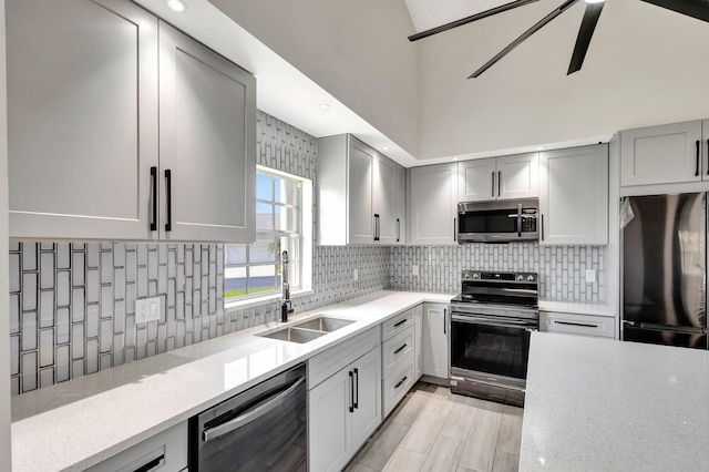 kitchen with appliances with stainless steel finishes, a sink, tasteful backsplash, and light stone counters