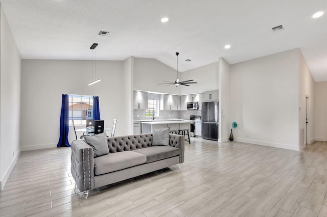 living room featuring high vaulted ceiling, baseboards, a ceiling fan, light wood finished floors, and recessed lighting