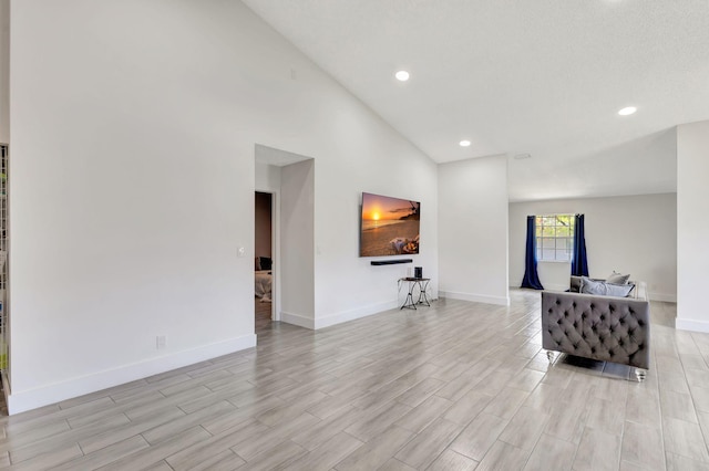 living area with light wood-style floors, baseboards, recessed lighting, and high vaulted ceiling