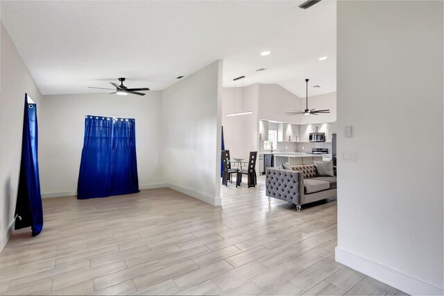 living room featuring a ceiling fan, lofted ceiling, baseboards, and light wood finished floors