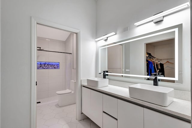 full bath with double vanity, toilet, a stall shower, a spacious closet, and tile patterned flooring