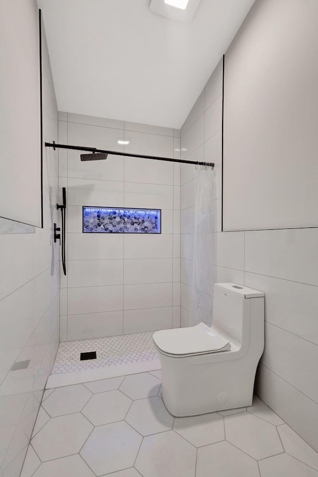 bathroom featuring a tile shower, toilet, tile walls, and tile patterned floors