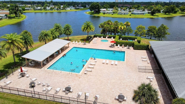 community pool featuring fence, a water view, and a patio area