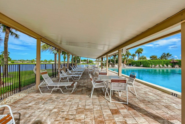 view of patio with fence, a community pool, and a water view