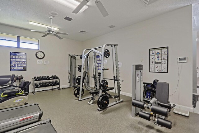 workout area featuring ceiling fan, baseboards, and a textured ceiling