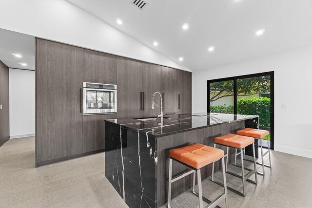 6878 Touchstone Cir, Palm Beach Gardens, FL 33418 - kitchen with a kitchen bar, high vaulted ceiling, a sink, oven, and a large island with sink