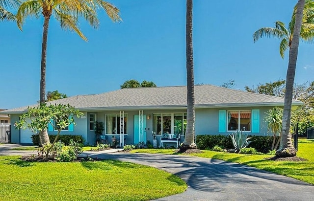 ranch-style house with fence, a front yard, and curved driveway