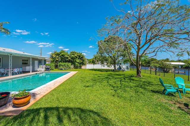 view of swimming pool featuring fence, a patio, a yard, and a fenced in pool