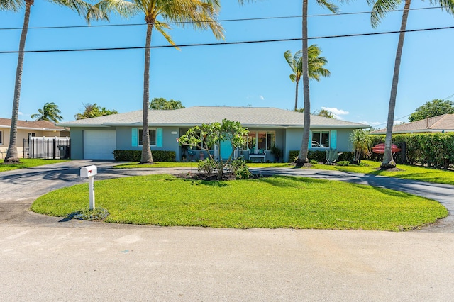 ranch-style home featuring a front lawn, driveway, fence, an attached garage, and stucco siding
