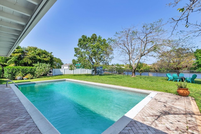view of pool featuring a patio area, a lawn, a water view, a fenced backyard, and a fenced in pool