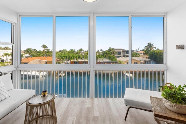 sunroom / solarium featuring a water view and wood finished floors