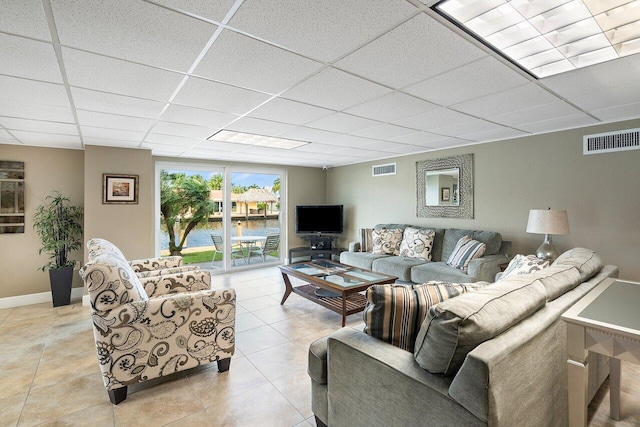 living room with light tile patterned floors, baseboards, a drop ceiling, and visible vents