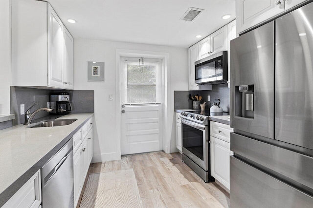 kitchen featuring a sink, stainless steel appliances, white cabinetry, light wood-type flooring, and visible vents