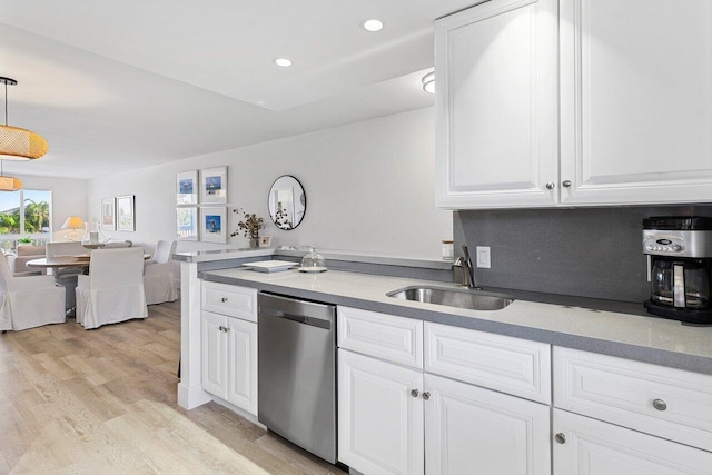 kitchen with stainless steel dishwasher, white cabinets, a sink, and light wood-type flooring