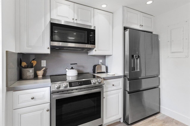 kitchen featuring light wood-style floors, light countertops, stainless steel appliances, baseboards, and white cabinetry