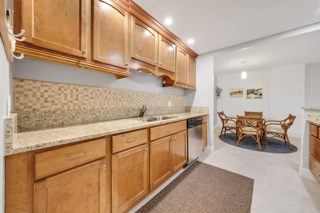 kitchen with tasteful backsplash, stainless steel dishwasher, light stone countertops, and a sink