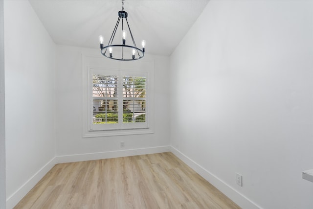 unfurnished dining area featuring light wood-type flooring, baseboards, and a notable chandelier
