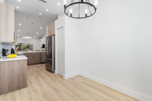 kitchen featuring an inviting chandelier, modern cabinets, light countertops, light wood-style flooring, and appliances with stainless steel finishes