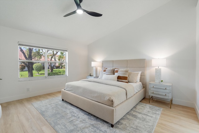 bedroom with baseboards, vaulted ceiling, and light wood finished floors