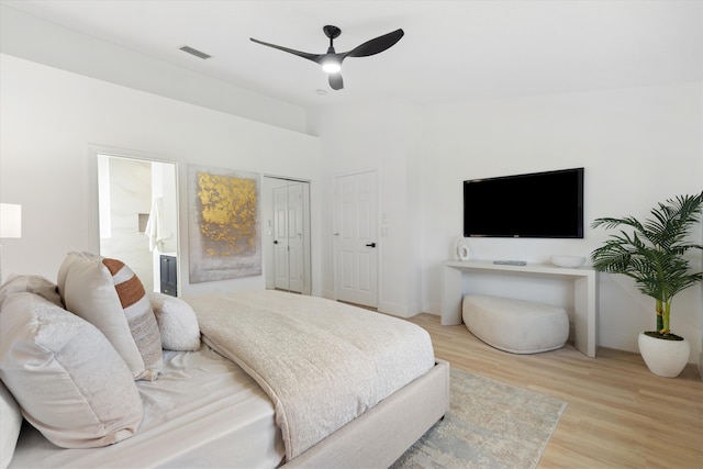 bedroom featuring ensuite bath, a ceiling fan, baseboards, wood finished floors, and visible vents