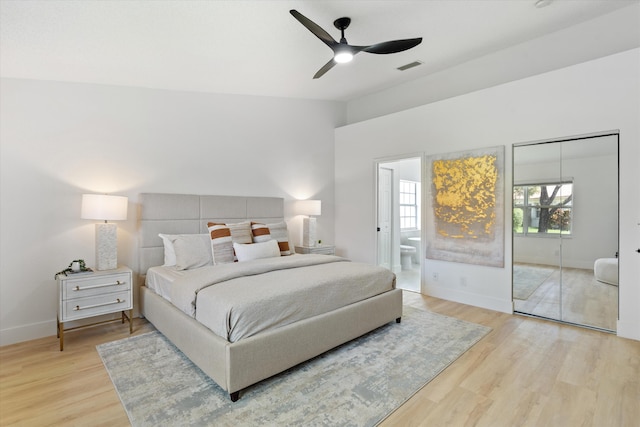 bedroom featuring connected bathroom, light wood finished floors, a ceiling fan, baseboards, and visible vents