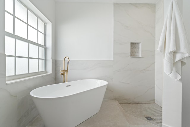 bathroom featuring a freestanding tub, tile walls, and a shower