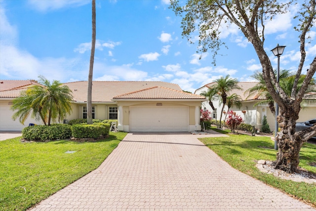 ranch-style house with a front lawn, a tile roof, a garage, stucco siding, and decorative driveway
