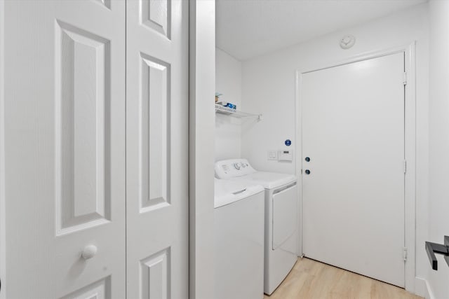 laundry room with separate washer and dryer, laundry area, and light wood-style flooring